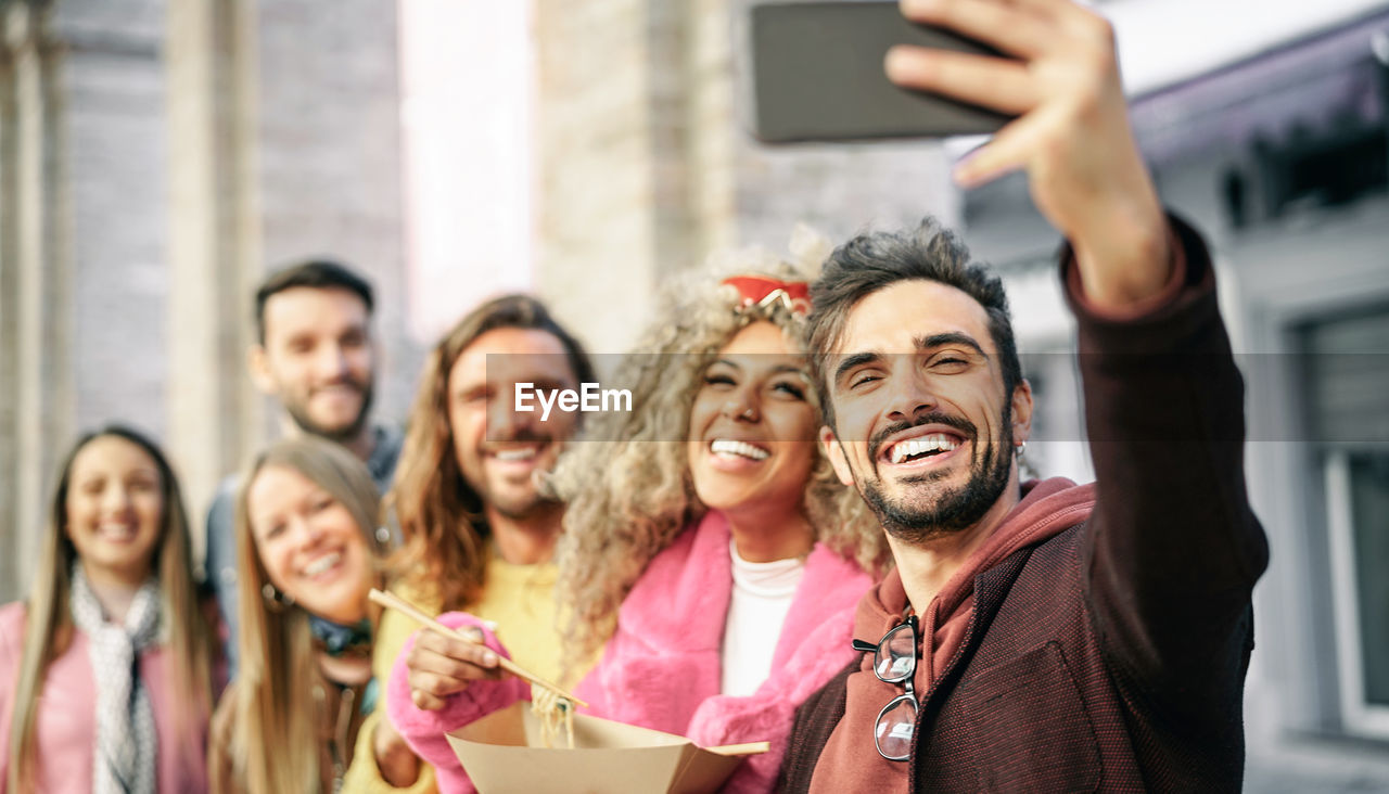 Man taking selfie with friends on mobile phone