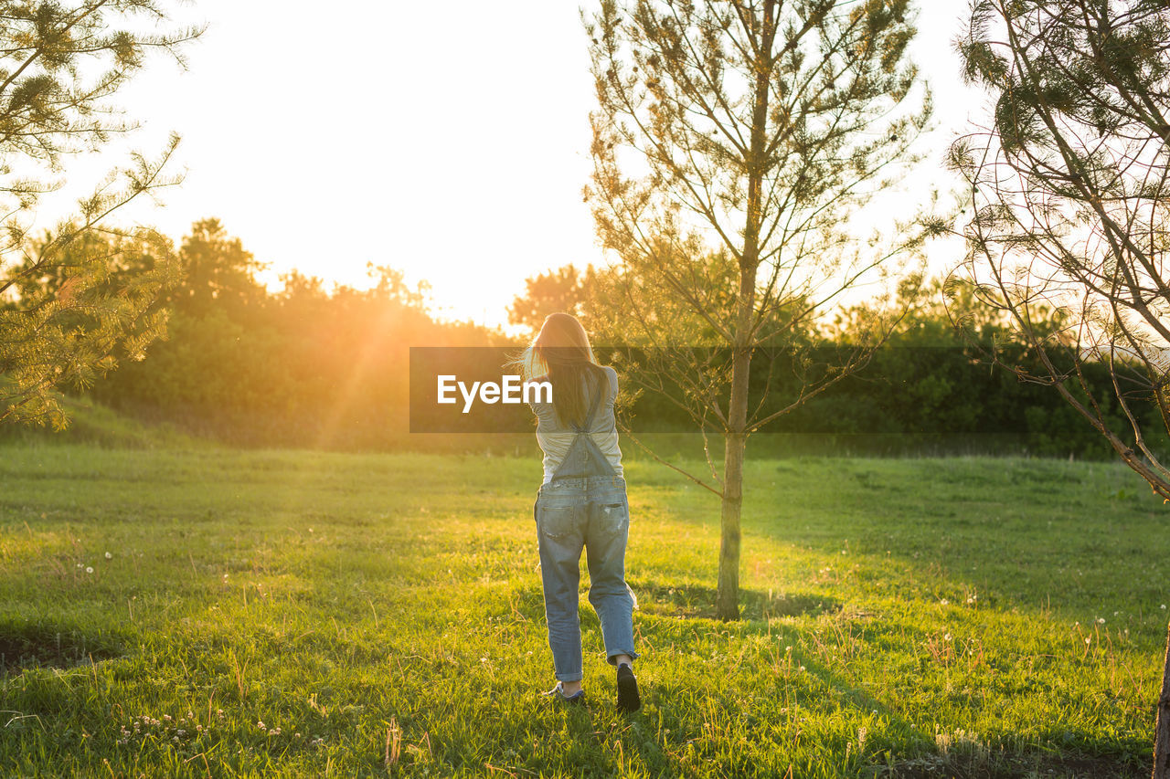 REAR VIEW OF PERSON STANDING ON FIELD