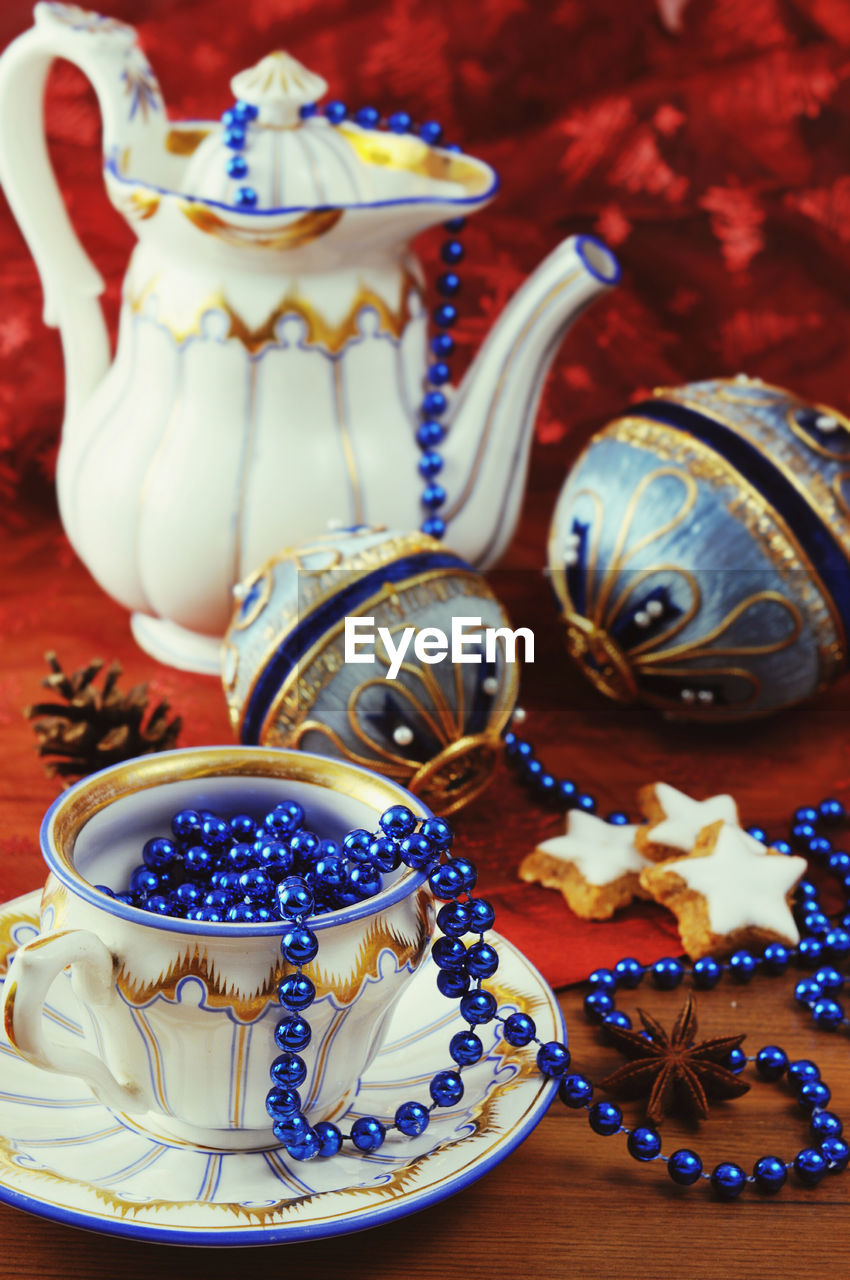 Close-up of christmas baubles by antique crockery with bead jewelry on table