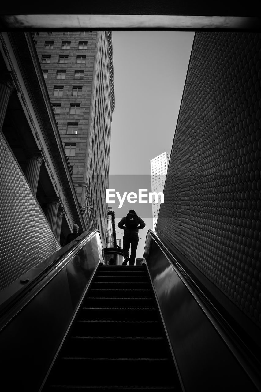 REAR VIEW OF PEOPLE WALKING ON ELEVATED WALKWAY