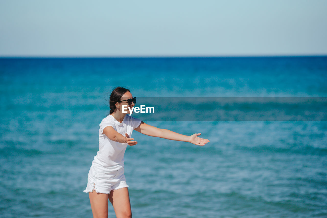 side view of young woman standing at beach