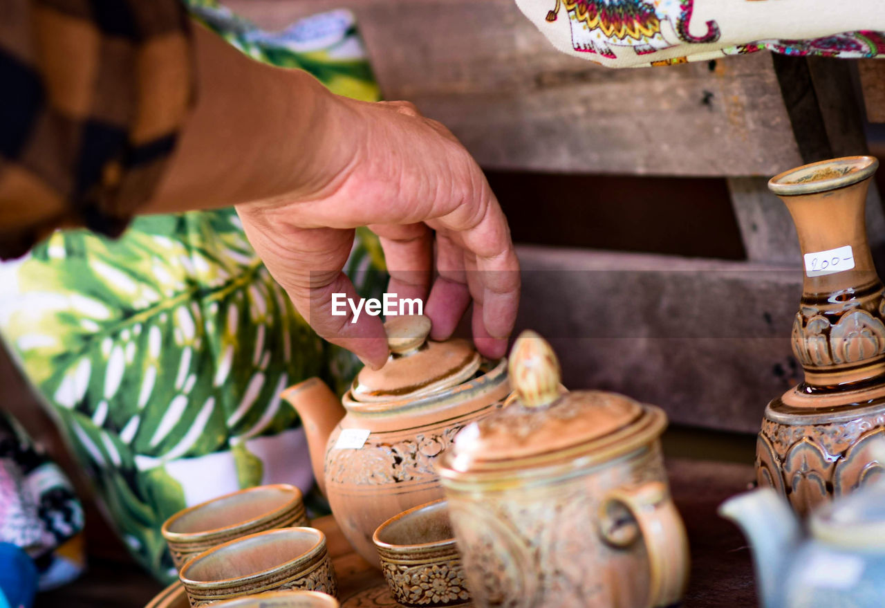 Cropped hand of person holding lid of teapot