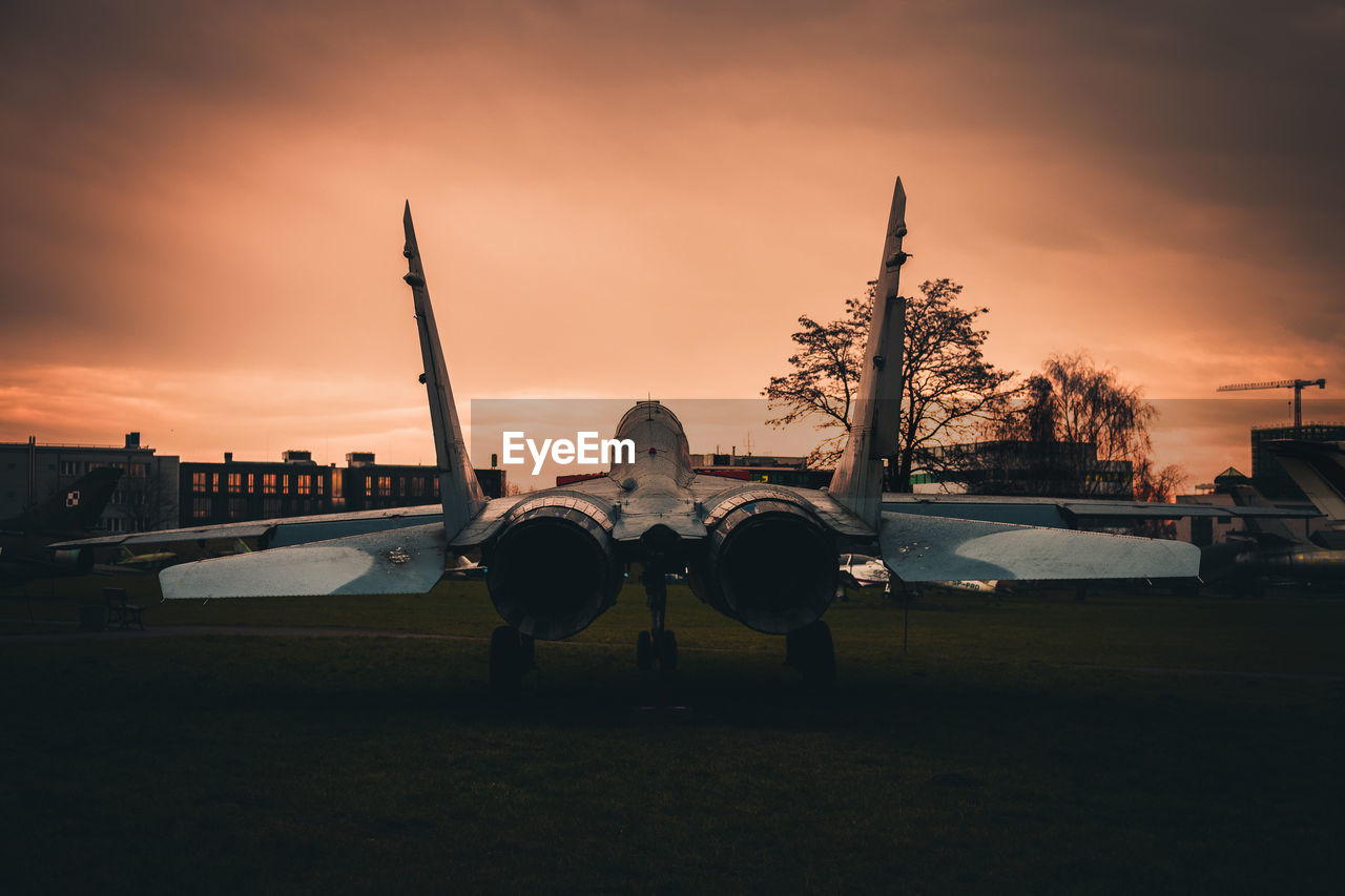 Airplane on runway against sky during sunset