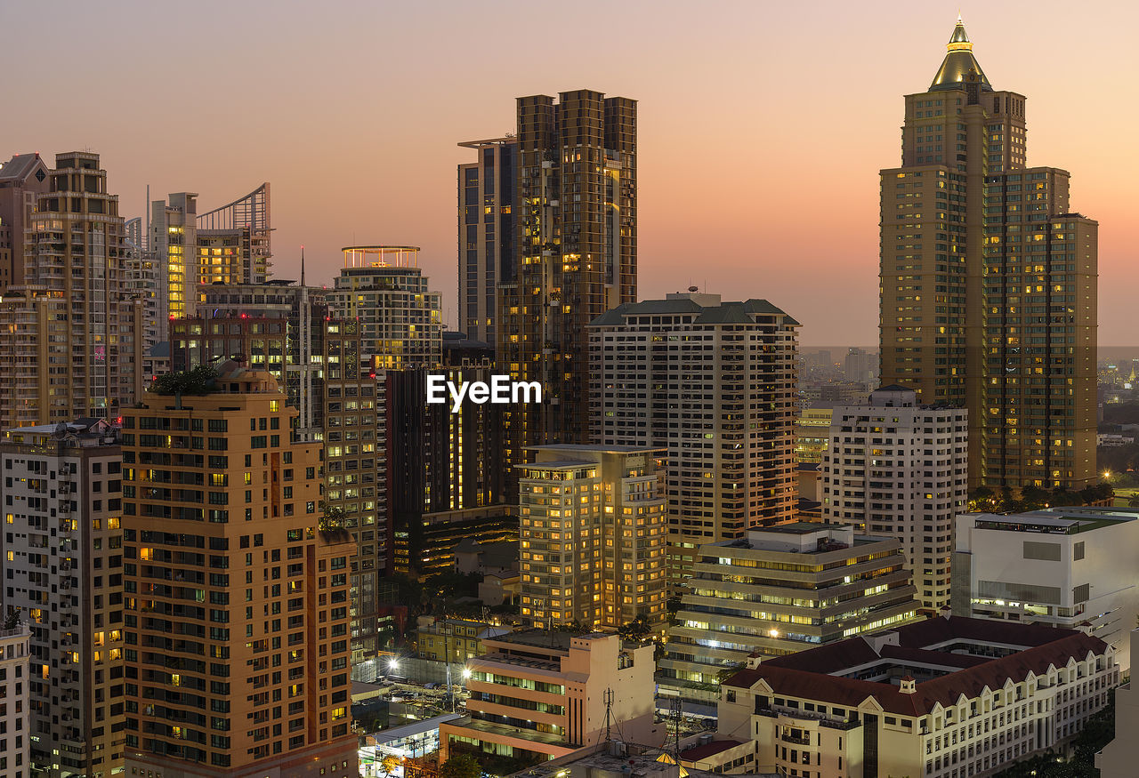 MODERN BUILDINGS IN CITY AGAINST SKY DURING SUNSET