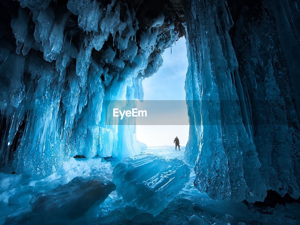 Distant view of man standing in frozen cave