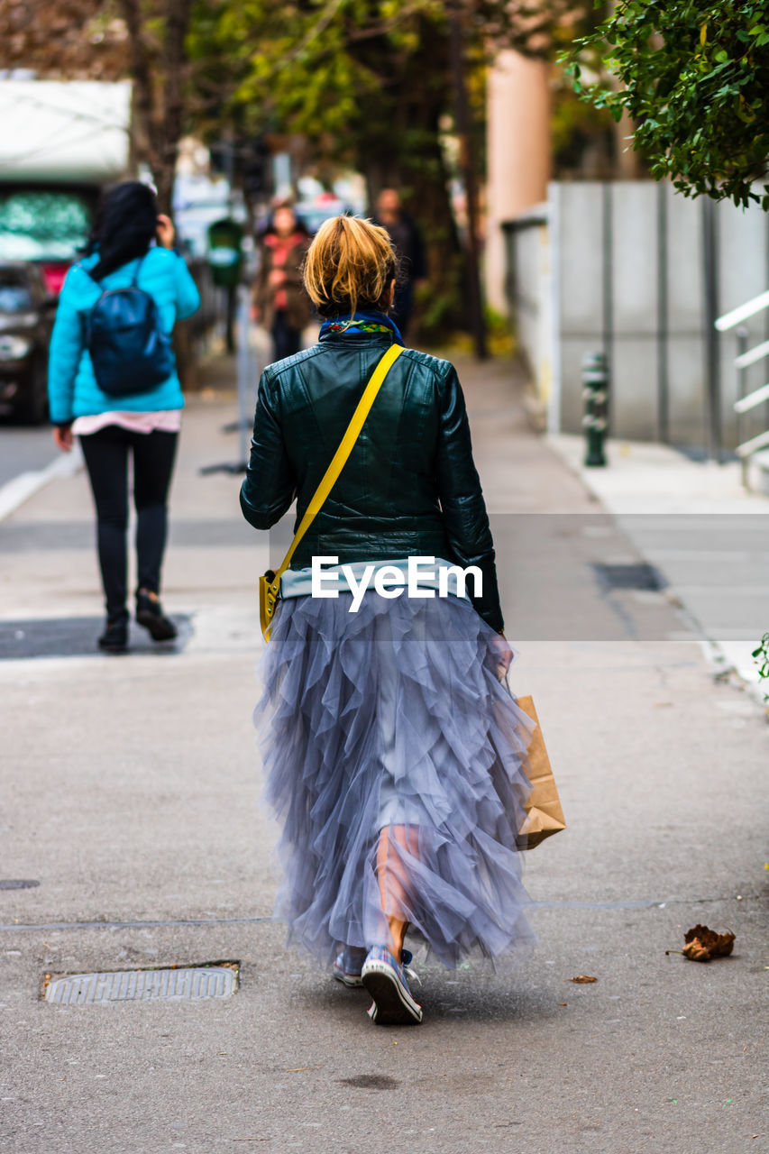 REAR VIEW OF WOMAN WALKING ON FOOTPATH