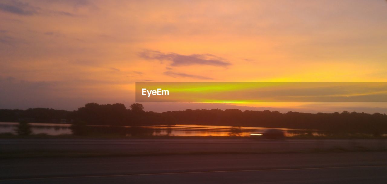 SCENIC VIEW OF CALM LAKE AT SUNSET