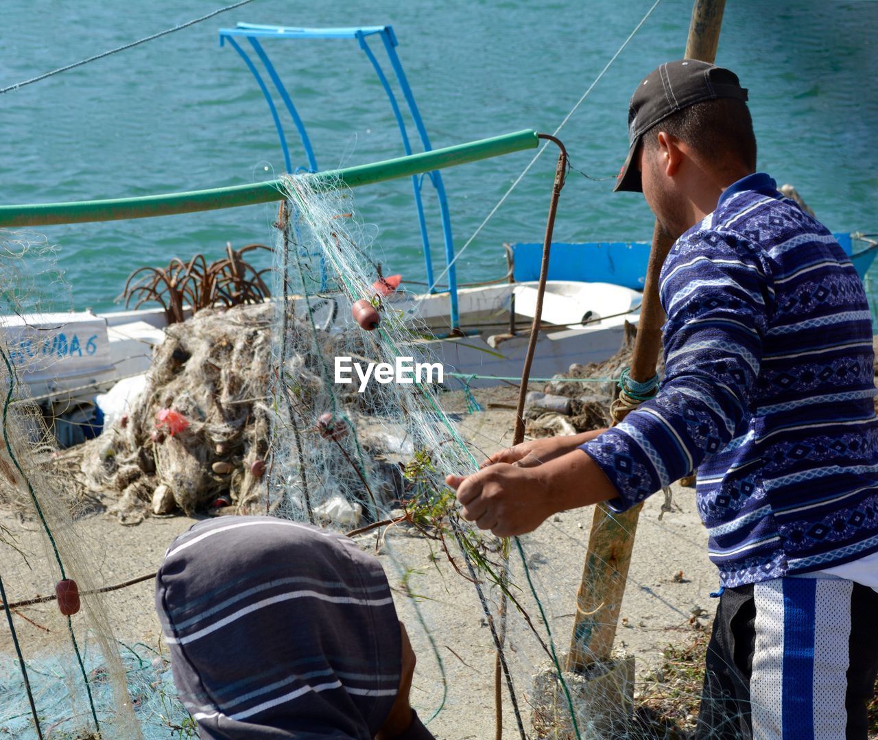 Fisherman holding fishing net on pier against clear sky