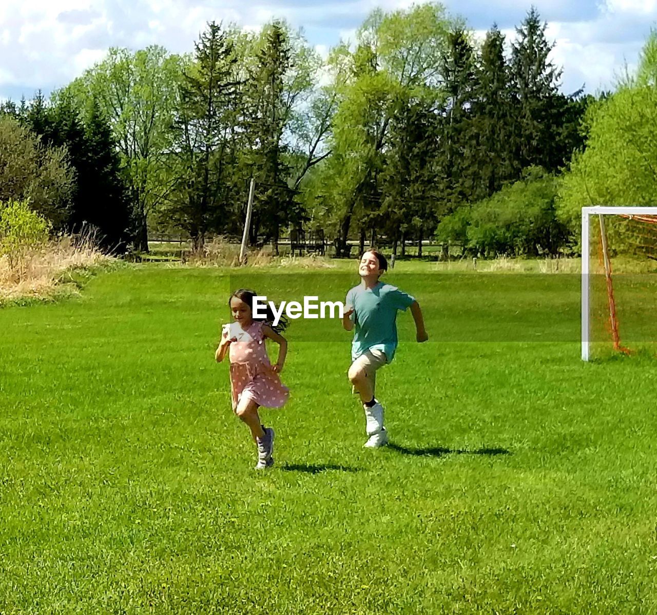 grass, plant, sports, child, green, full length, childhood, soccer, nature, team sport, men, tree, leisure activity, day, togetherness, female, two people, meadow, casual clothing, motion, lifestyles, sky, ball, women, lawn, soccer ball, cloud, soccer field, sports equipment, person, sunlight, adult, outdoors, playground, enjoyment, fun, playing field, family, running, activity, field, sports clothing, friendship, bonding
