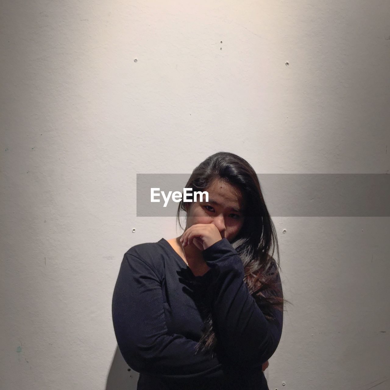 Portrait of young woman standing against wall