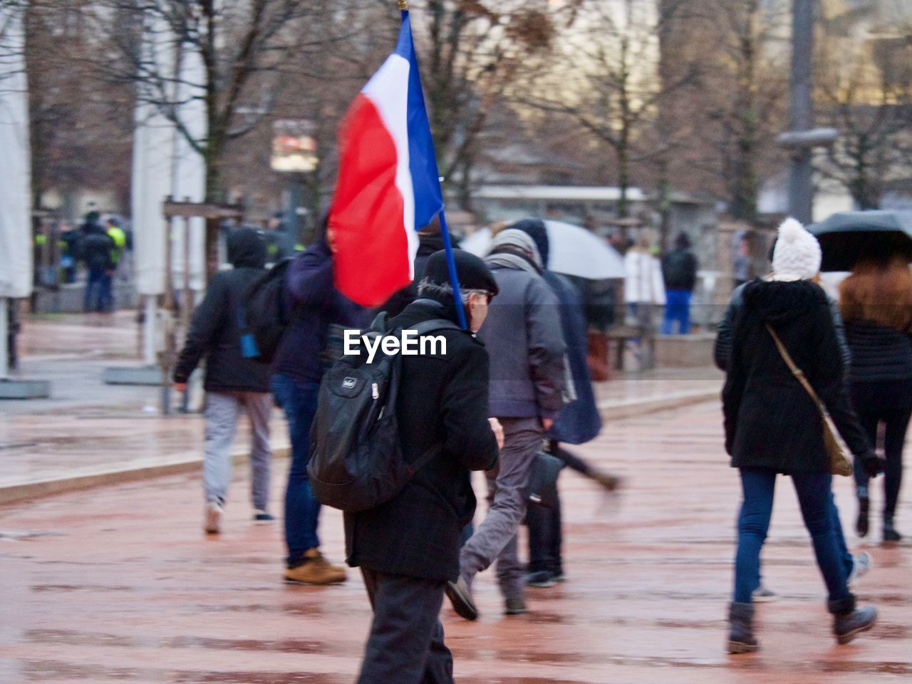 REAR VIEW OF PEOPLE WALKING ON STREET AGAINST TREES