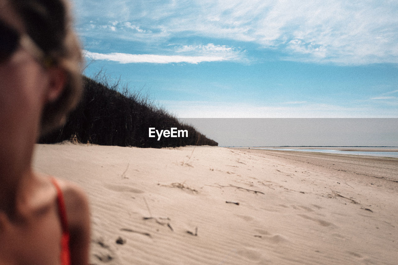 Close-up of woman standing on beach against sky