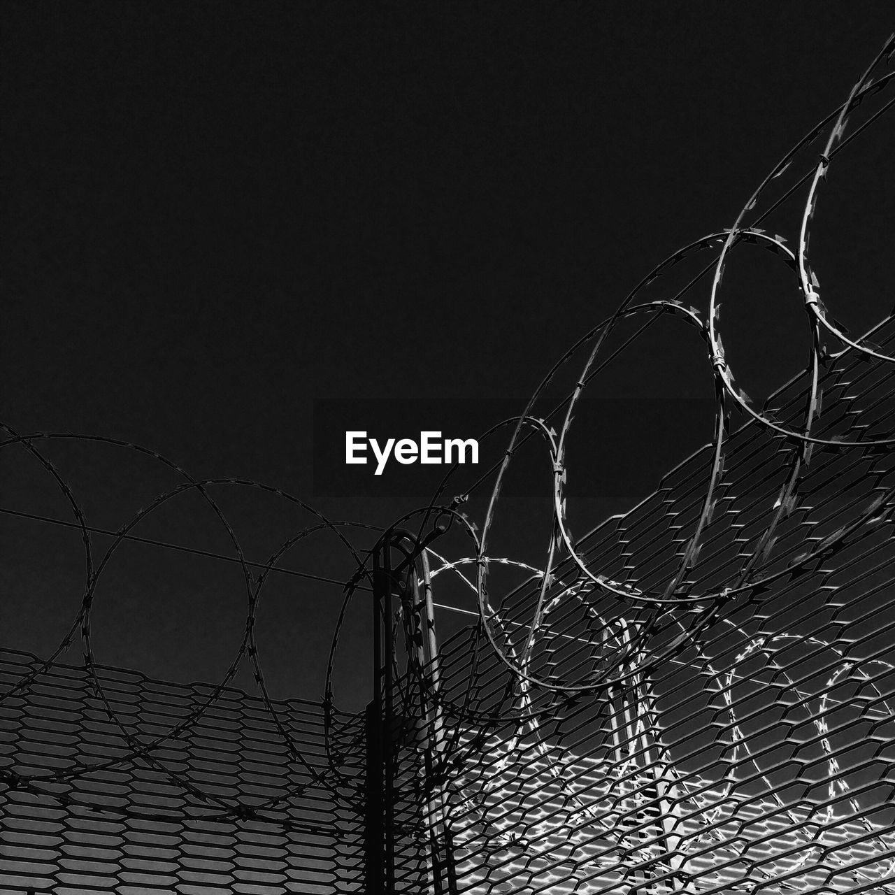 Low angle view of barbed wire fence against sky