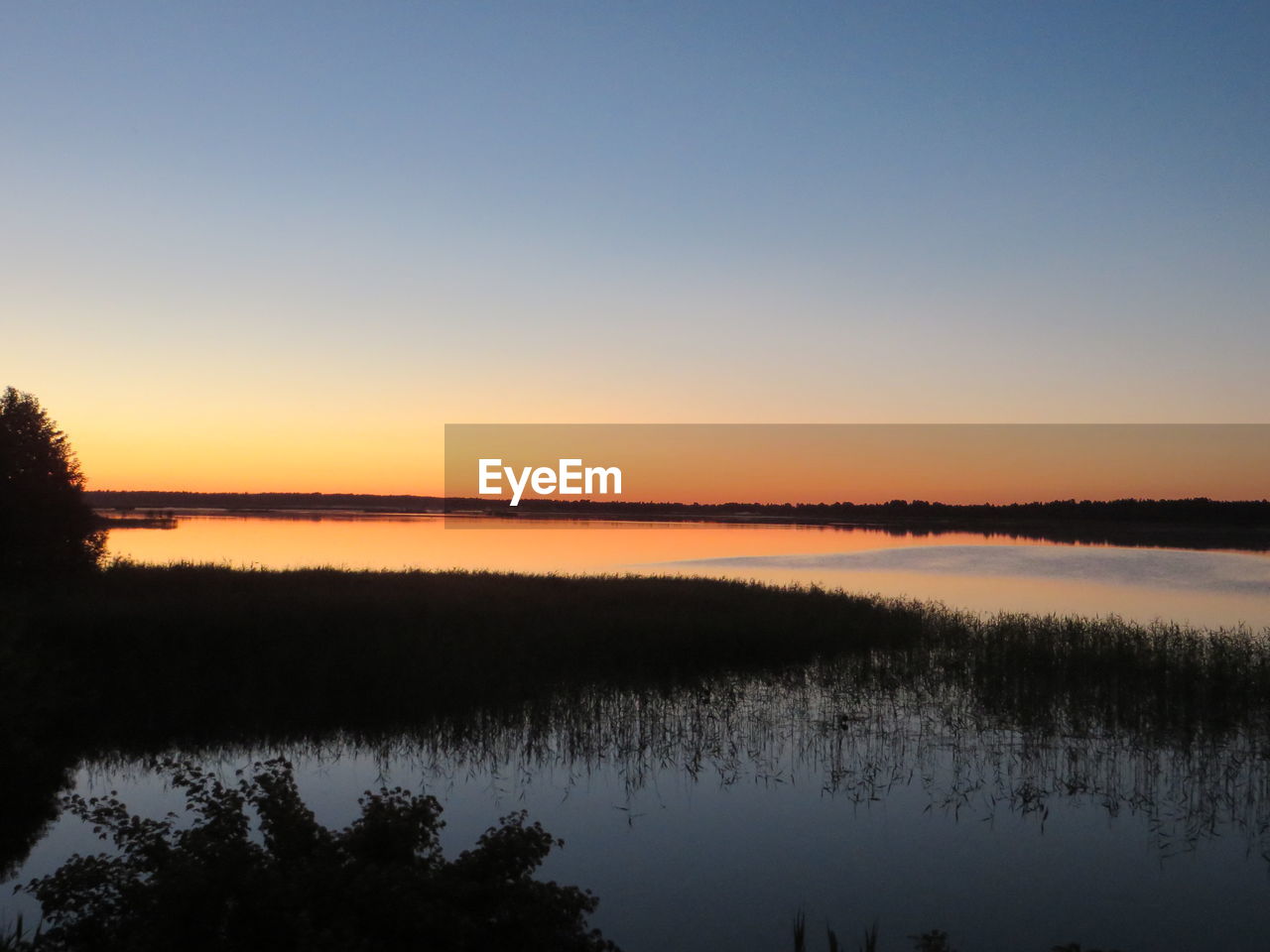 Scenic view of calm lake at sunset