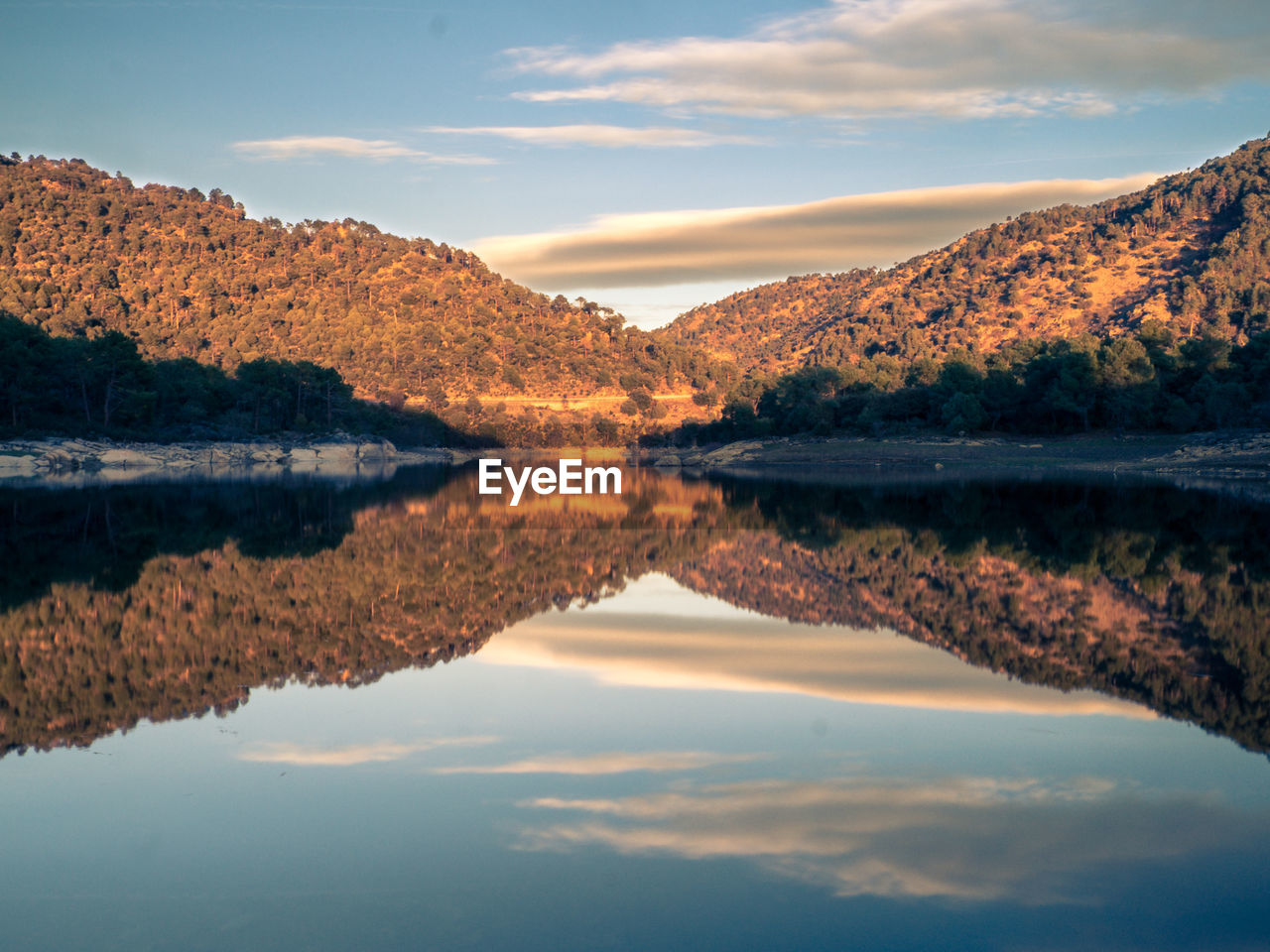 REFLECTION OF MOUNTAIN IN LAKE AGAINST SKY