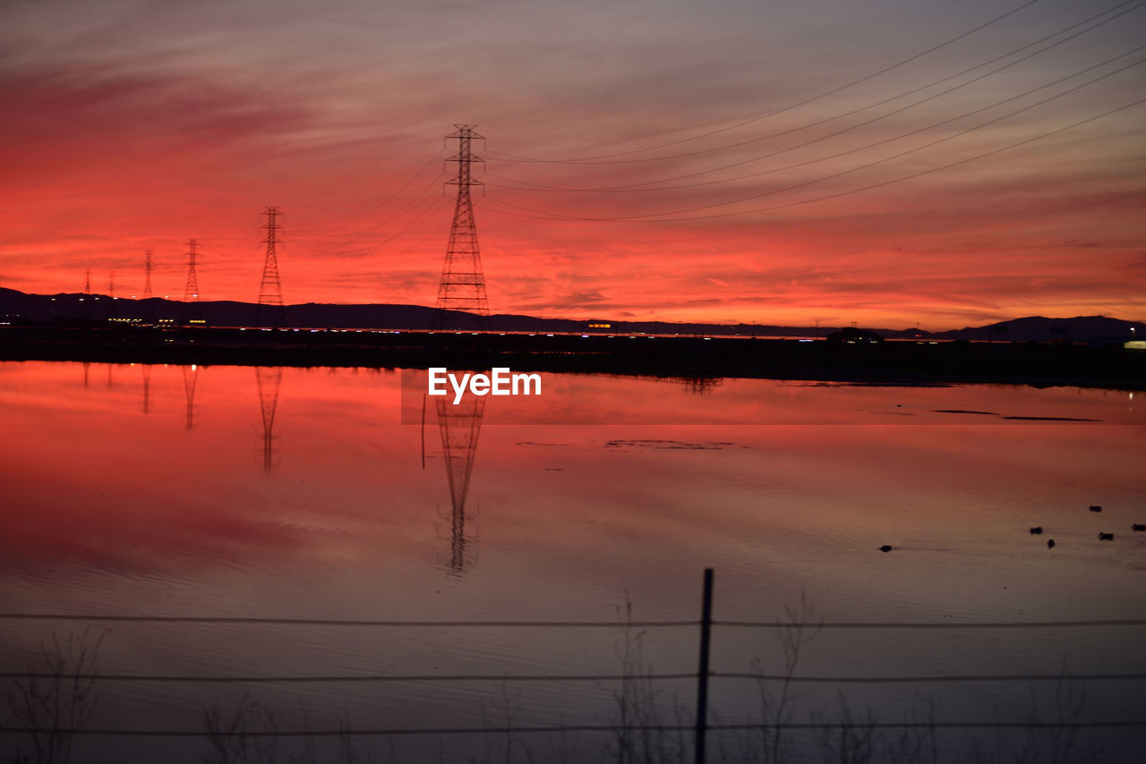 reflection, sky, sunrise, dawn, water, nature, cloud, afterglow, beauty in nature, horizon, technology, orange color, scenics - nature, cable, morning, electricity, silhouette, electricity pylon, tranquility, no people, industry, environment, tranquil scene, power line, dramatic sky, power supply, power generation, outdoors, architecture, landscape, sea, idyllic, built structure, transportation, business finance and industry, transmission tower