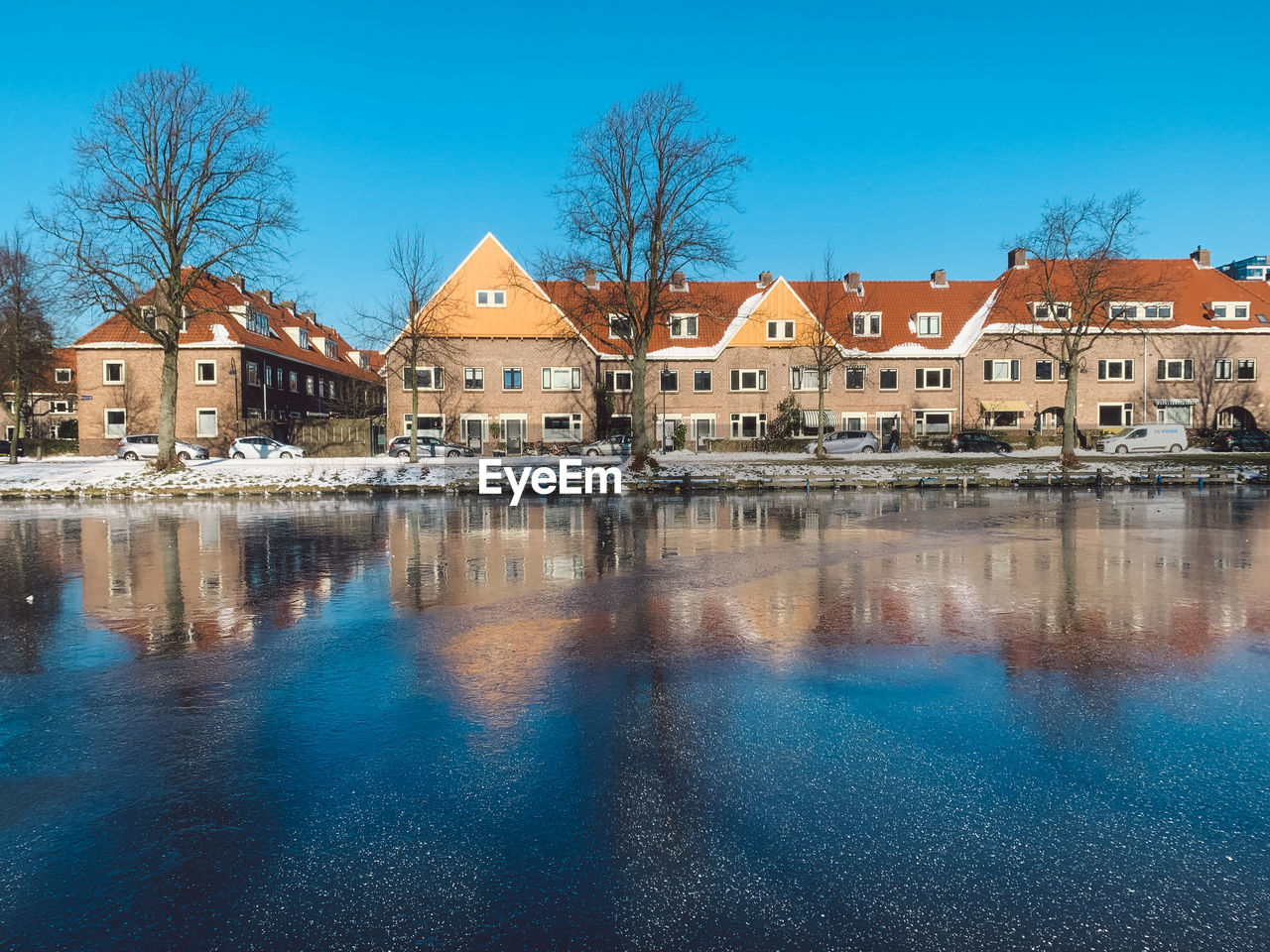 Canal by buildings against blue sky