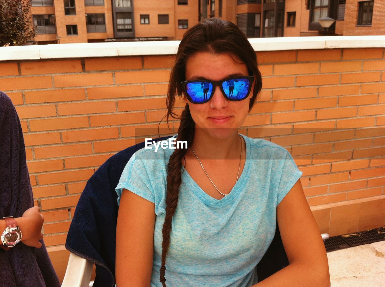 Portrait of young woman sitting on chair at building terrace