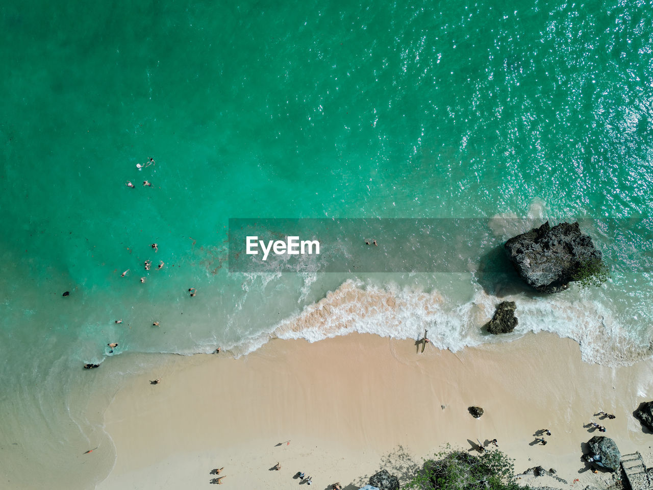 Aerial drone view of padang padang beach in bali with waves, rocks and forest