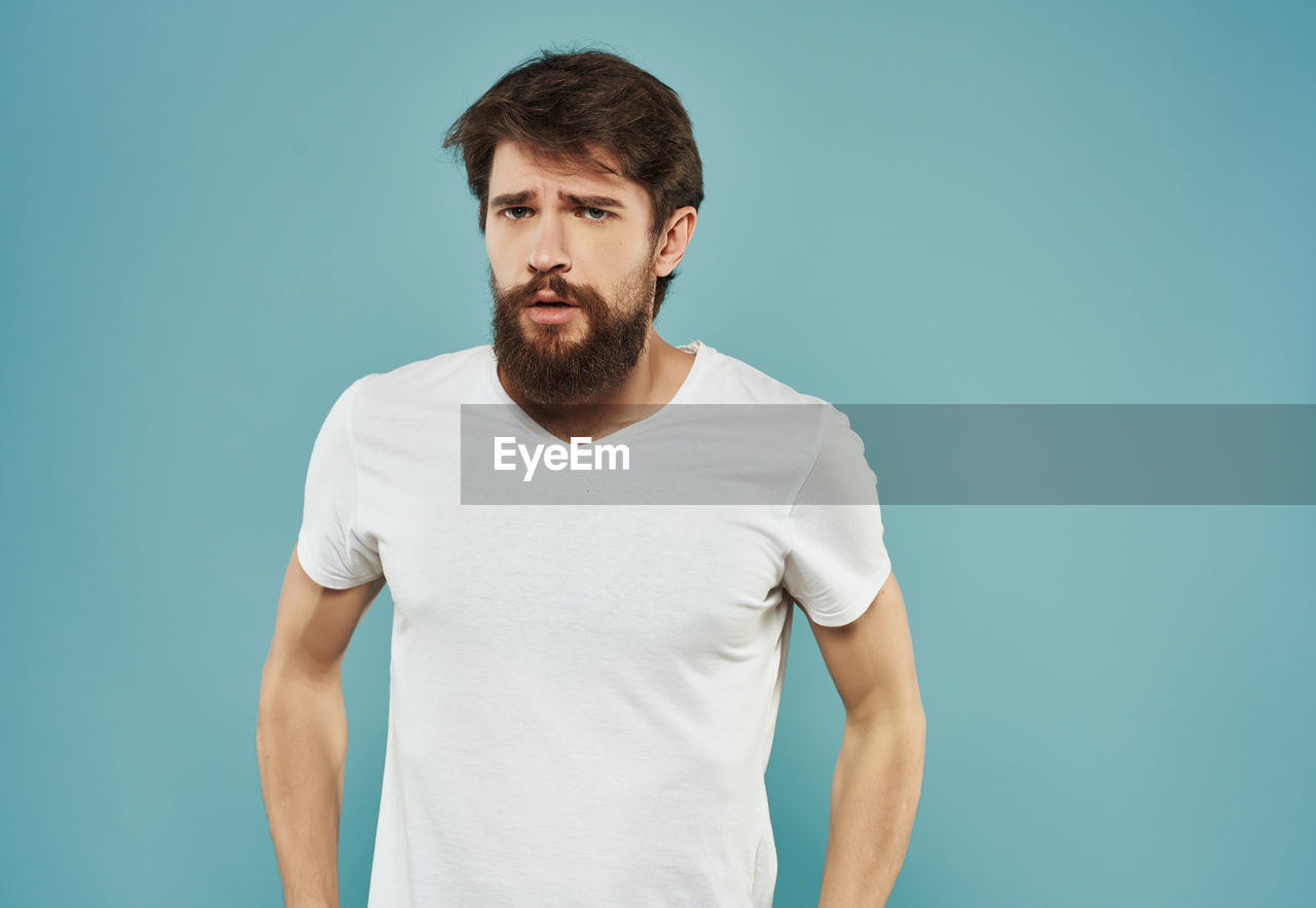 PORTRAIT OF MAN AGAINST BLUE BACKGROUND