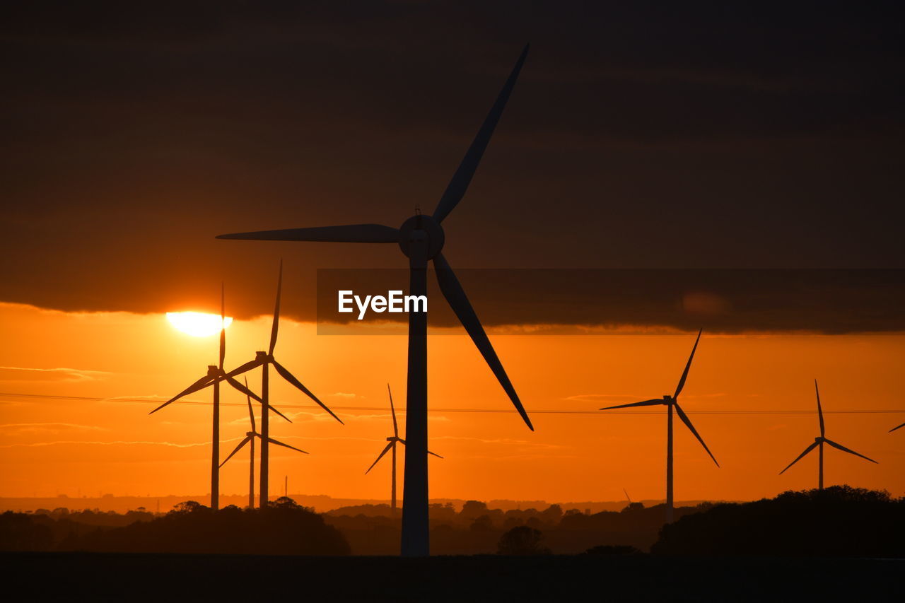 A bright red sunset through wind turbines