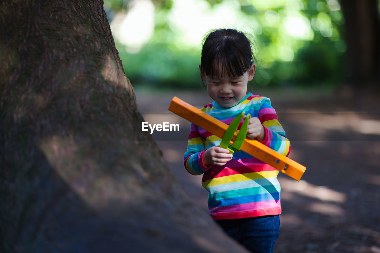 Young girl playing outdoor measure-mate in the forest park for leaning measurement