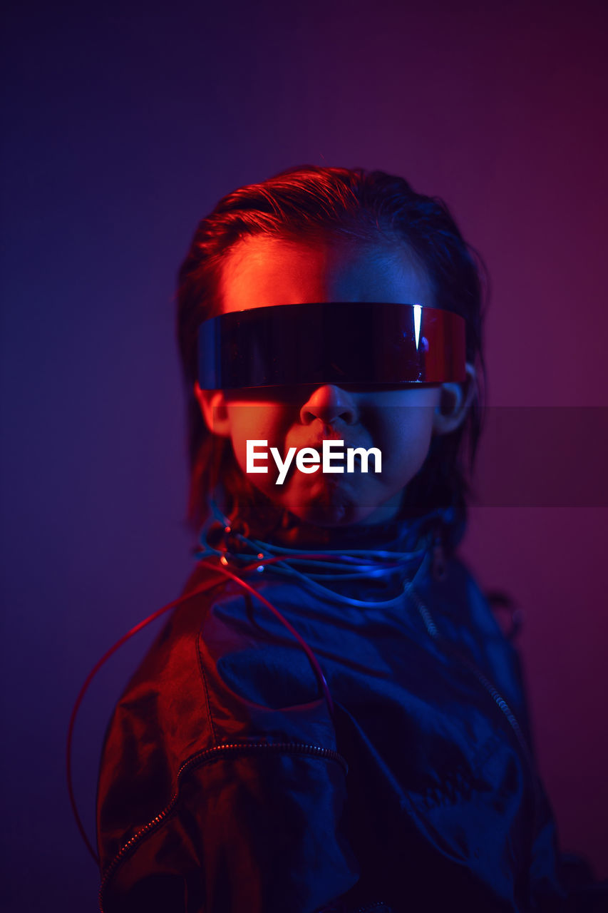 Portrait cyberpunk boy child in vr glasses in blue and red tones. game, virtual reality