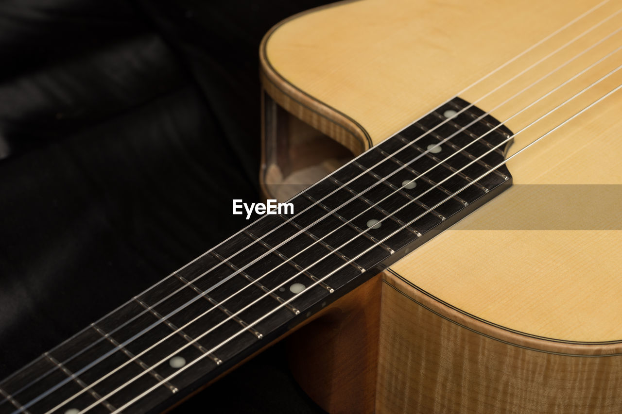 Cropped image of guitar on bed