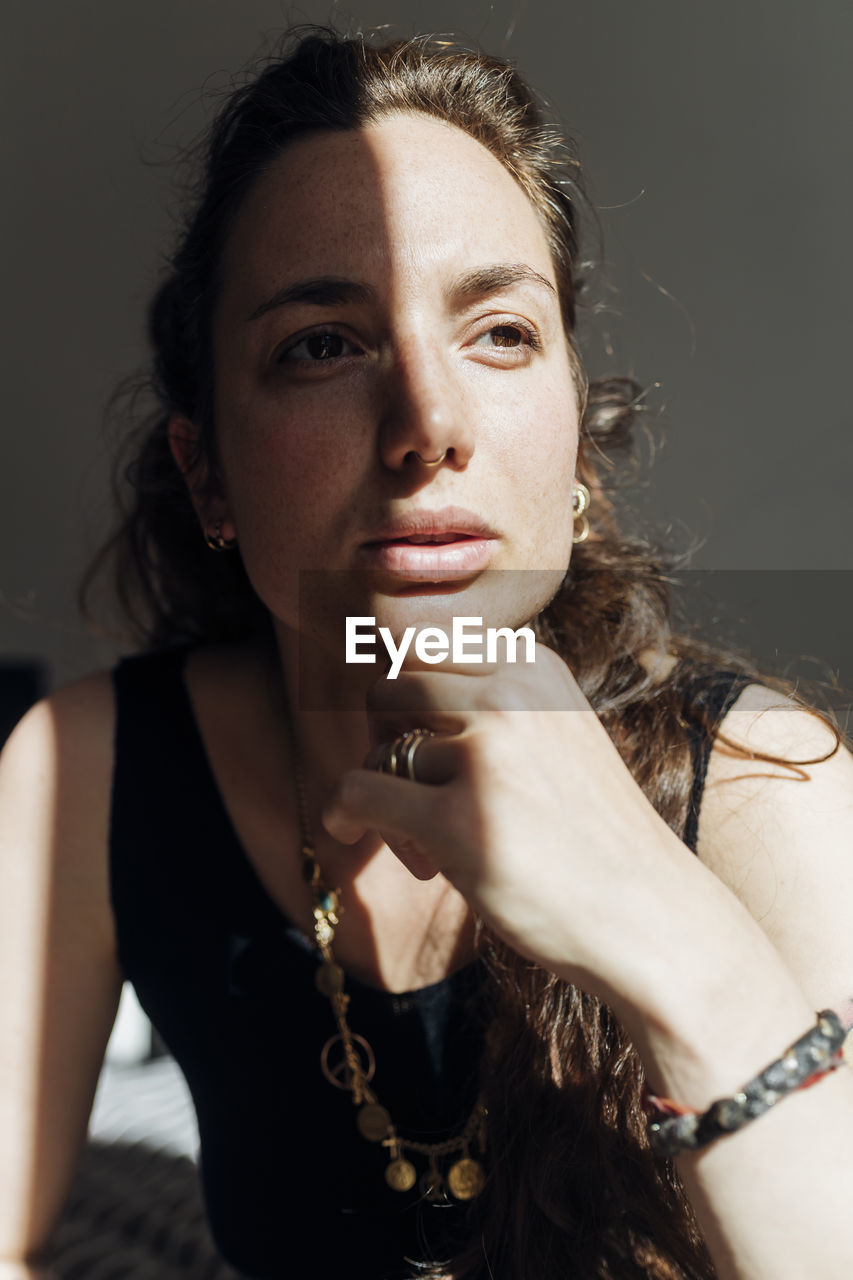 Thoughtful woman with hand on chin in apartment