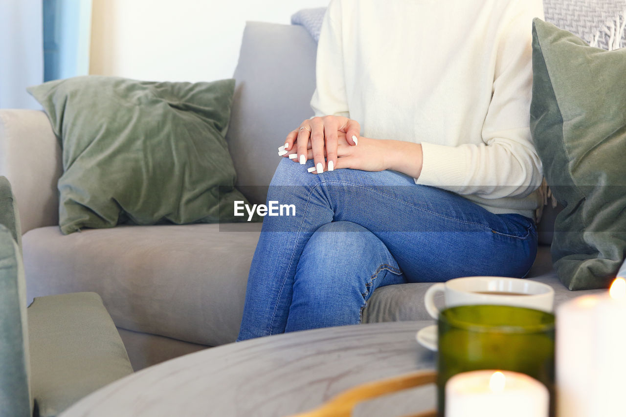 MIDSECTION OF MAN SITTING AT HOME