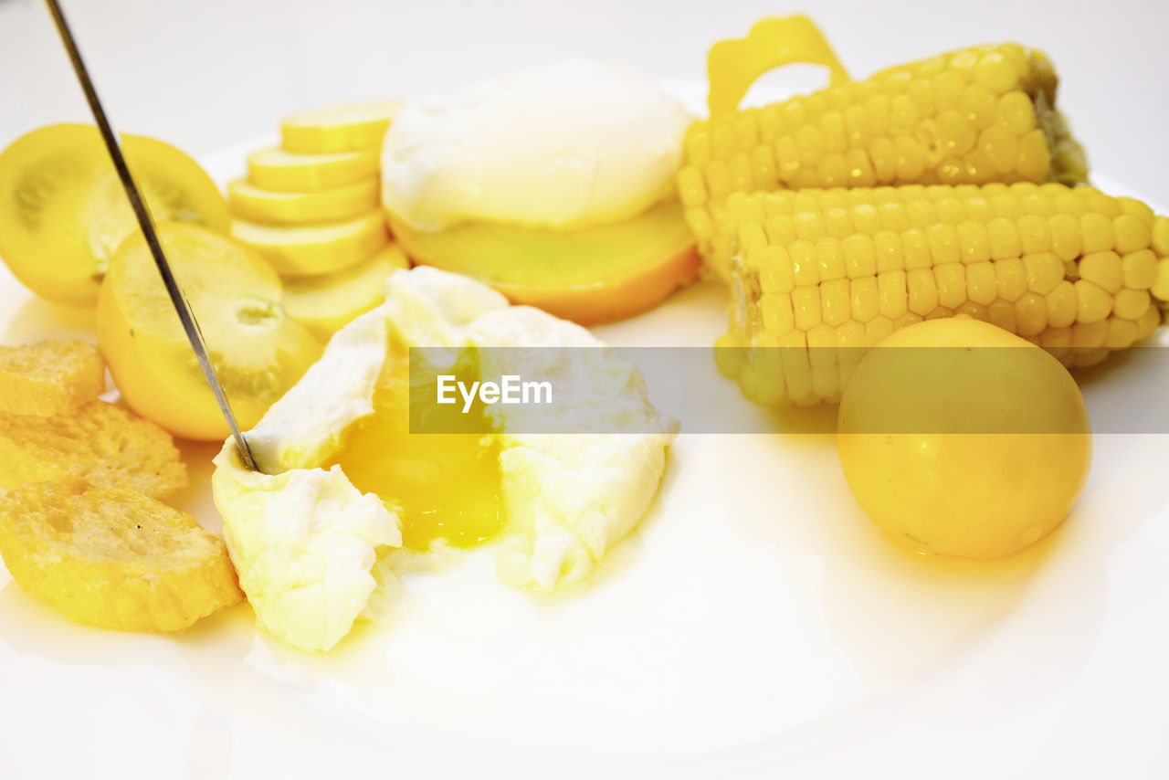 Poached egg on a plate with croutons, tomato and corn