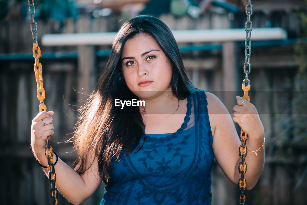 Portrait of young woman with long hair on swing