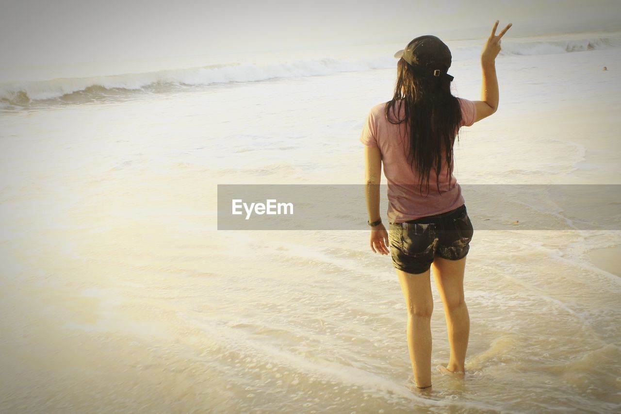 Rear view of woman standing at beach