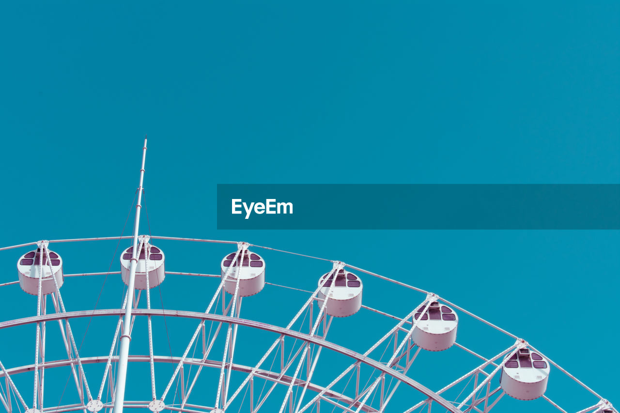 Low angle view of ferris wheel against blue sky