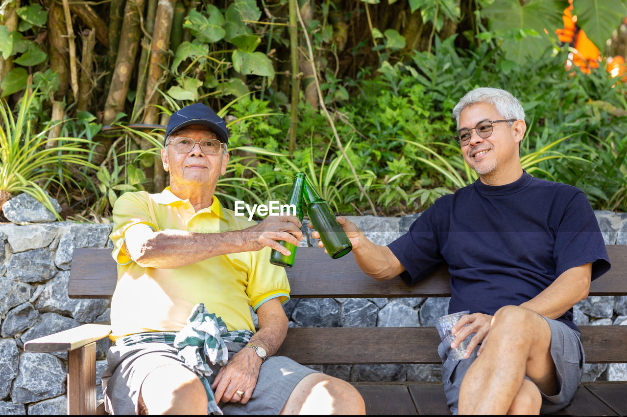 Father and son sitting in chairs and drinking beer on vacation.