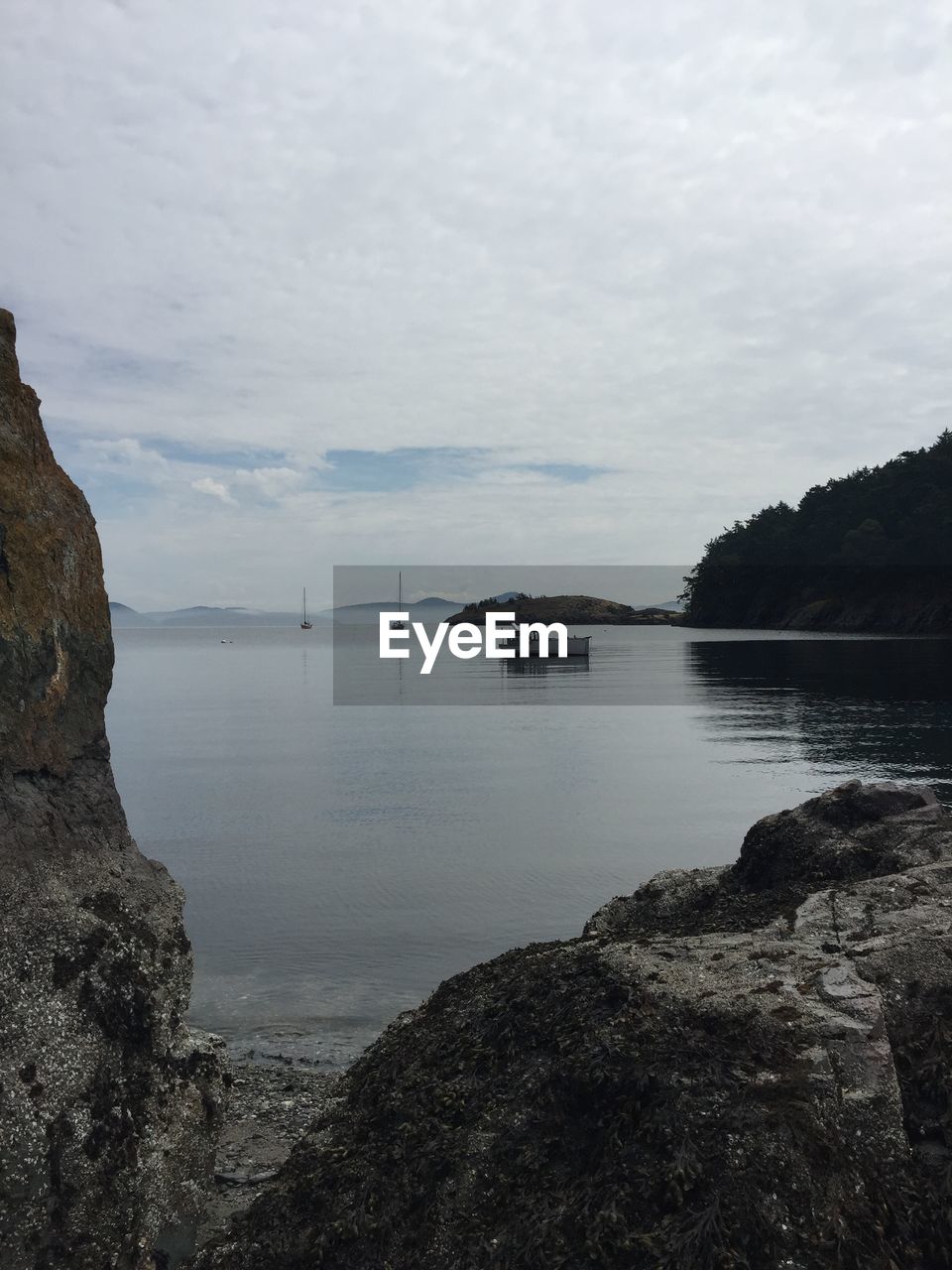 Rocky shore against cloudy sky