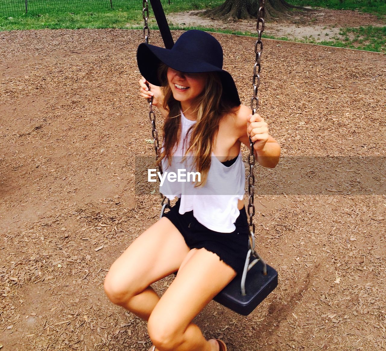 Smiling young woman sitting on swing at park