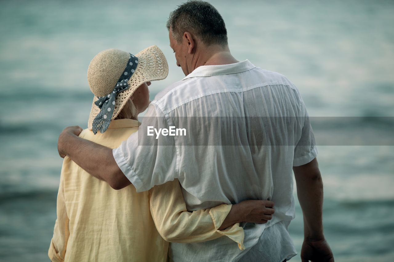 Rear view of mature couple standing at beach