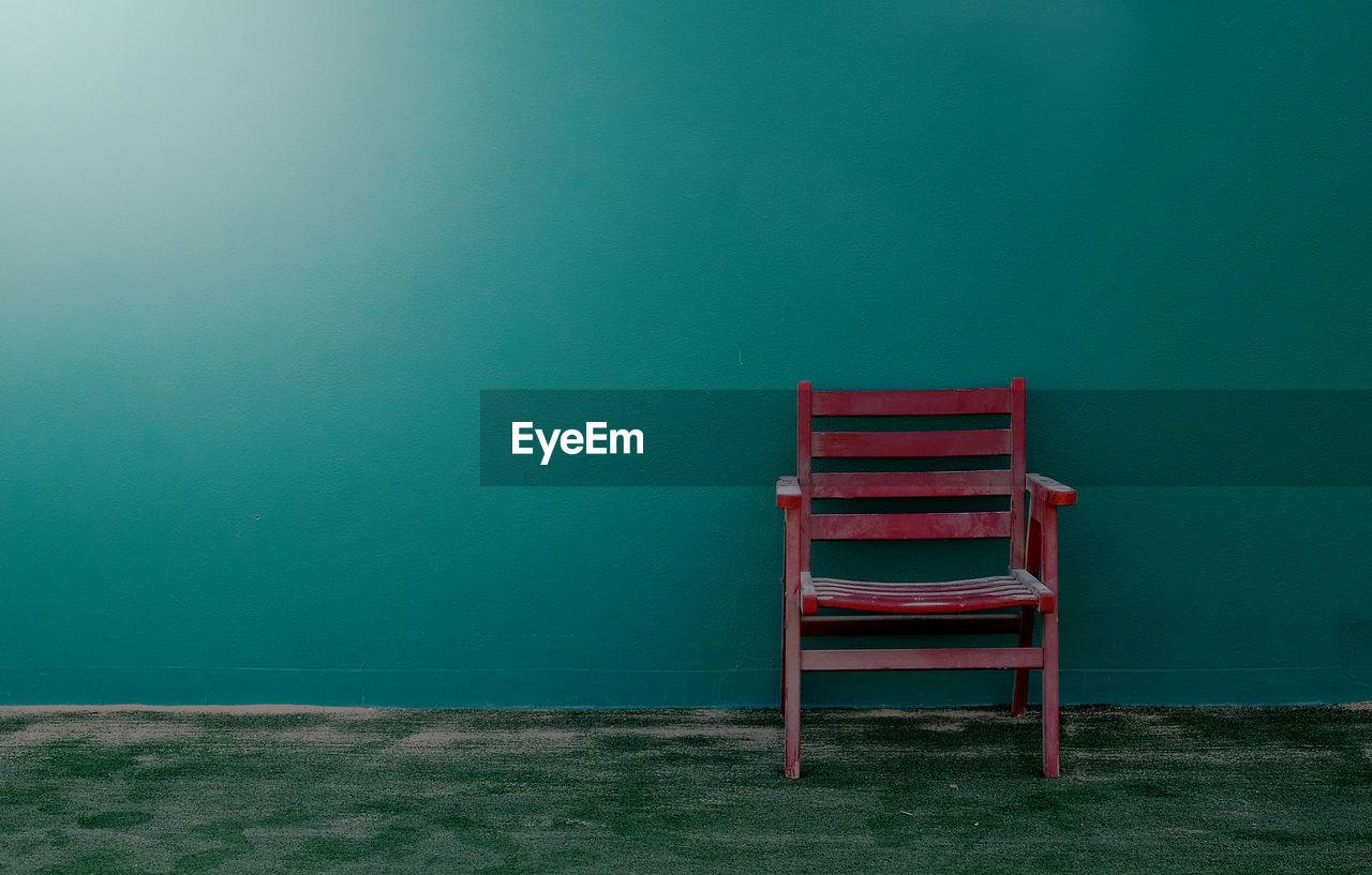 Red chair against green wall on tennis court 