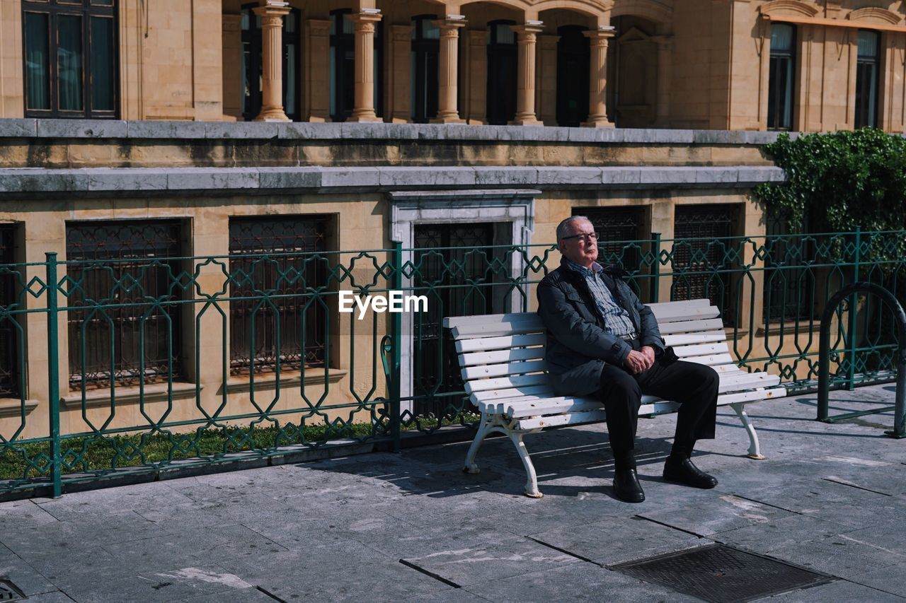 FULL LENGTH OF MAN SITTING AGAINST BUILDING