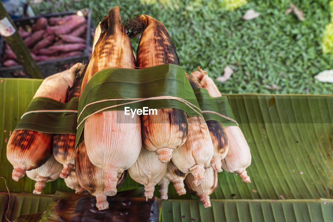 Baked corn tied with natural materials placed on a banana leaf.