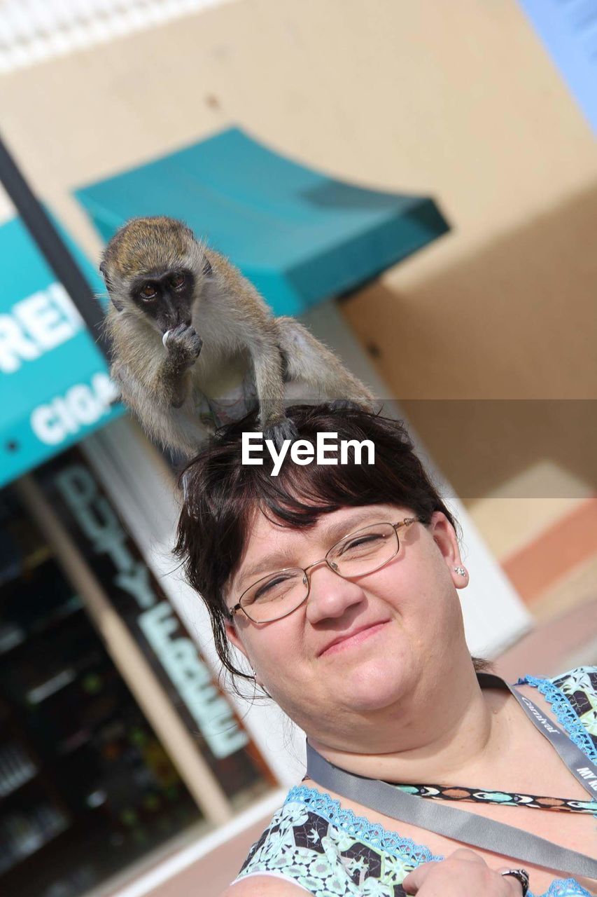 Portrait of woman carrying baboon on head