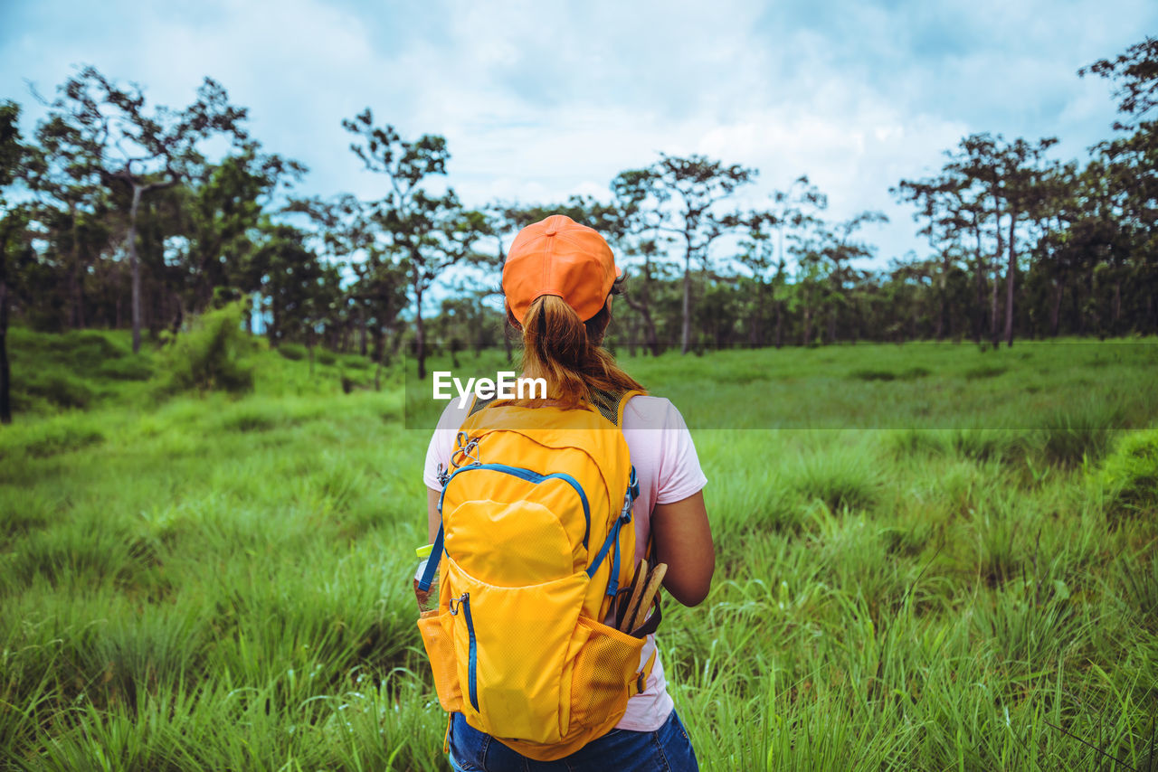 Rear view of woman with backpack standing on grassy land