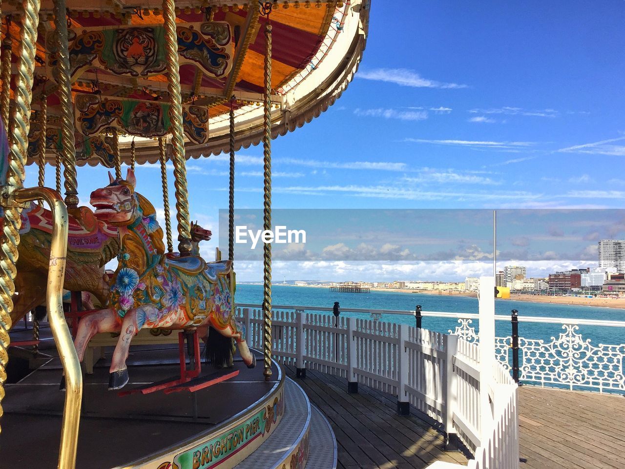 Carousel at amusement park by sea against sky