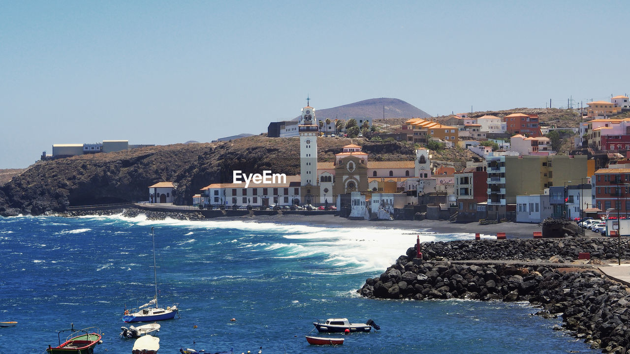 SCENIC VIEW OF SEA BY BUILDINGS AGAINST CLEAR SKY