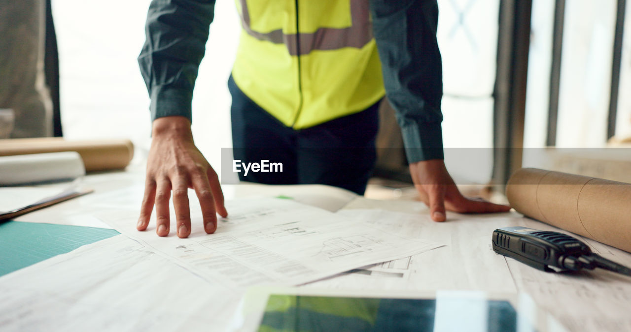 Hands of architect check blueprint at construction site for building.