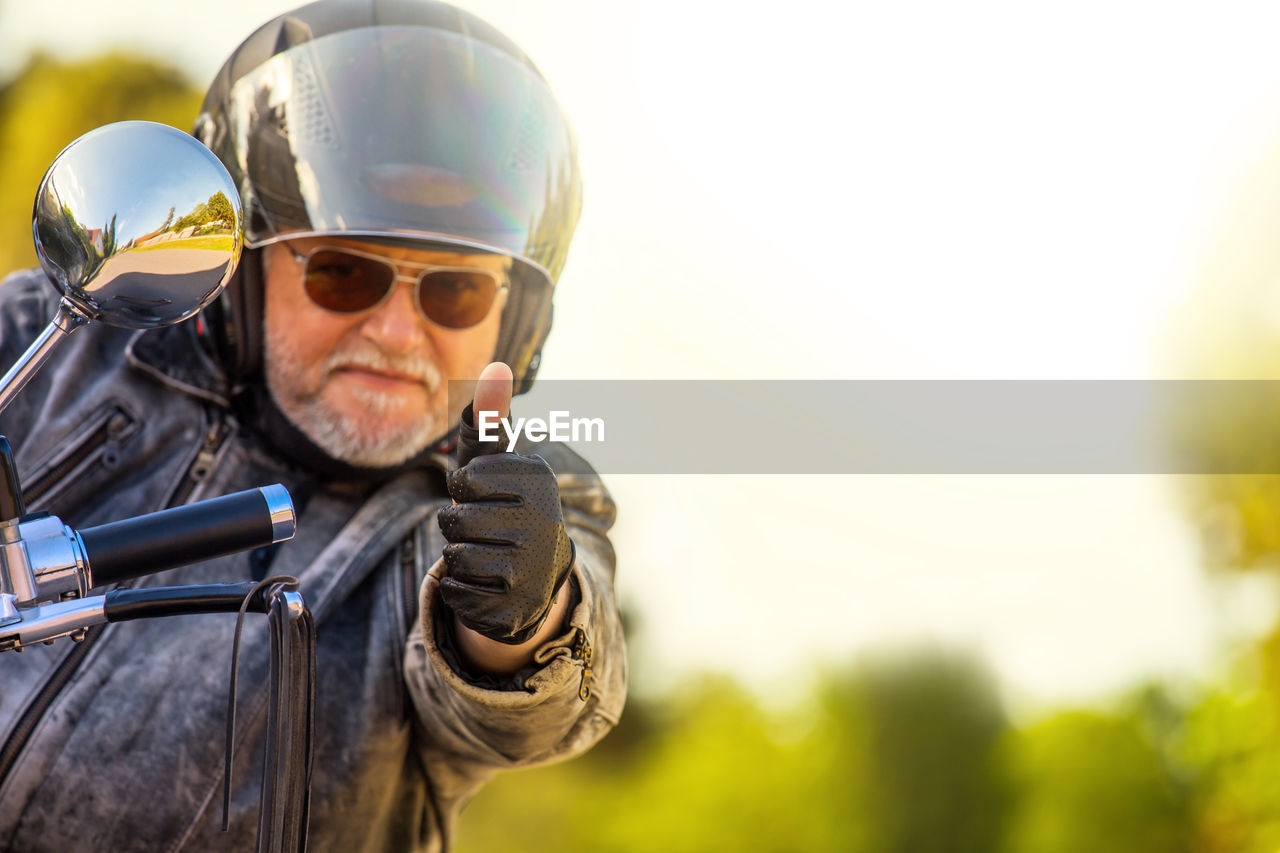 A motorcyclist with a helmet and sunglasses gives a friendly greeting