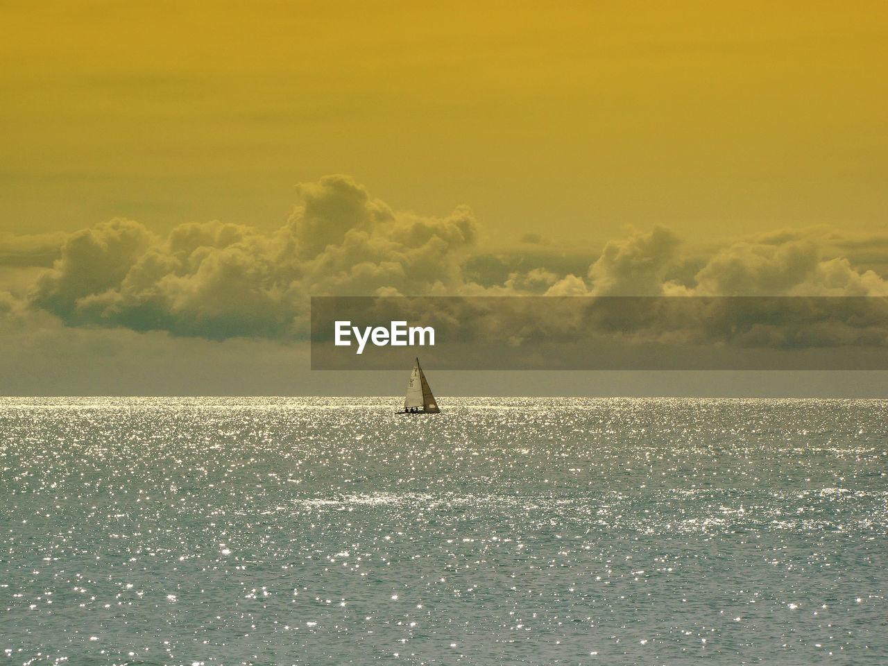 Mid distant view of sailboat sailing on seascape against sky during sunset