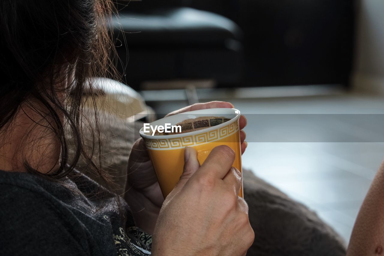 Midsection of woman holding coffee cup at home