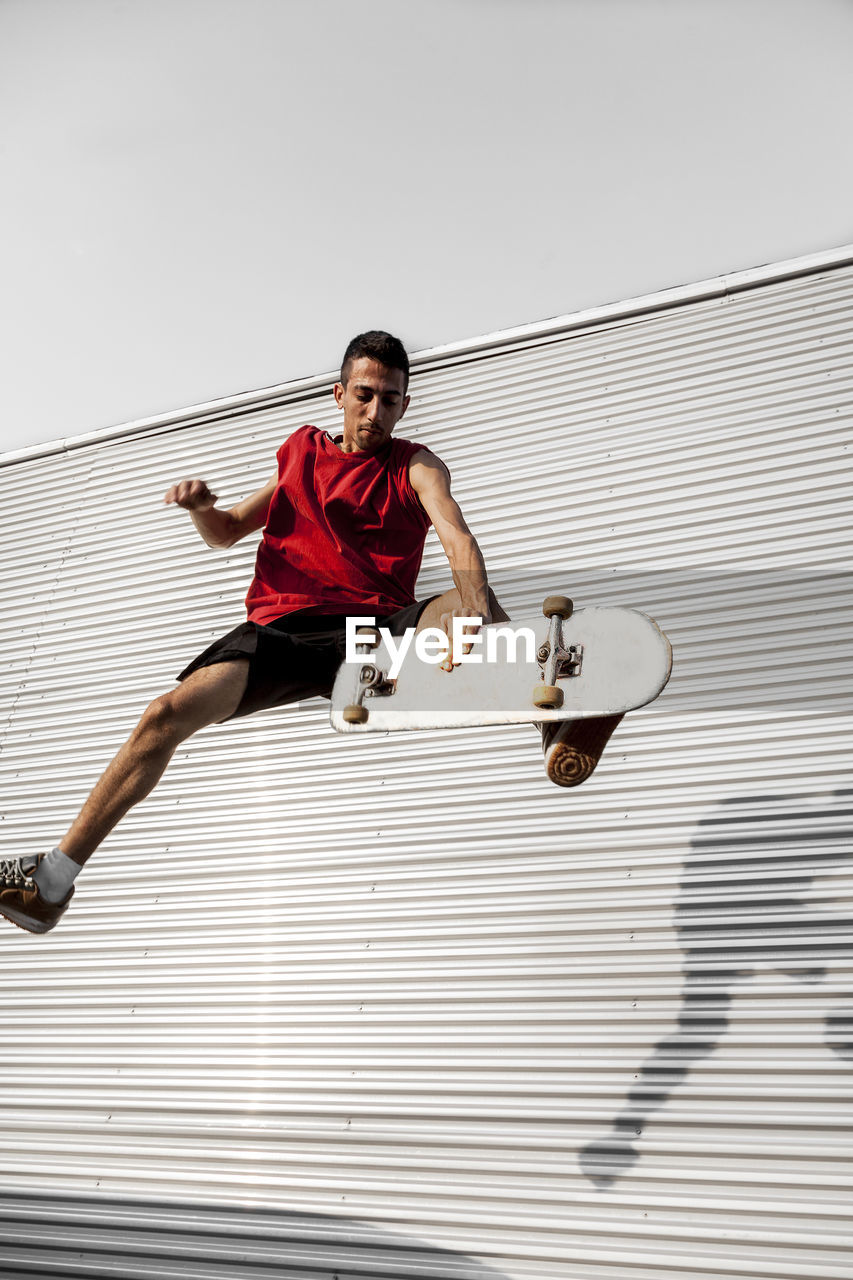 Man with skateboard in mid-air against wall